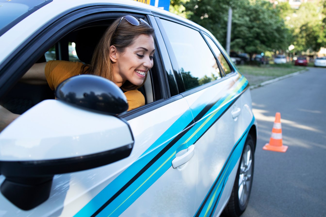 Happy woman learning to drive a car and going reverse. Car driving school and lessons.